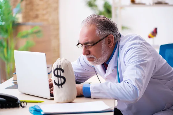 Stary lekarz trzymający torbę z pieniędzmi w szpitalu. — Zdjęcie stockowe