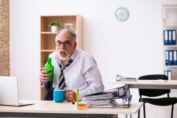 Starý muž zaměstnanec pití alkoholu v kanceláři — Stock fotografie