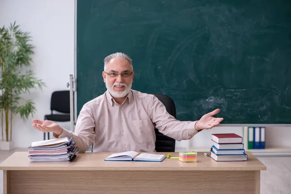 Oude mannelijke leraar zit in de klas — Stockfoto