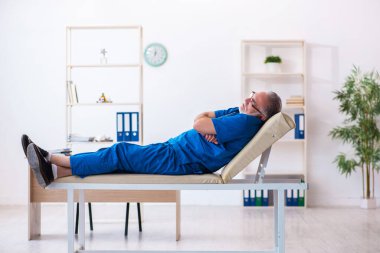 Yaşlı erkek doktor gece vardiyasından sonra çok yorgun.