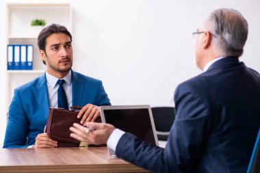 Genç bir erkek aday, yaşlı bir askerle görüşüyor.