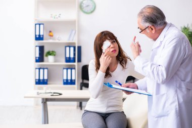 Genç kadın yaşlı erkek doktor göz doktorunu ziyaret ediyor.
