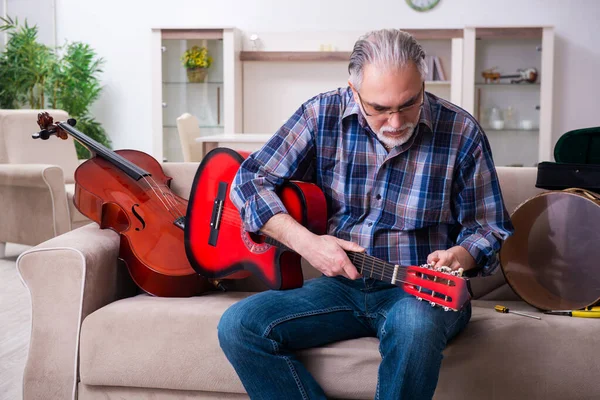 Hombre mayor reparador reparando instrumentos musicales en casa — Foto de Stock