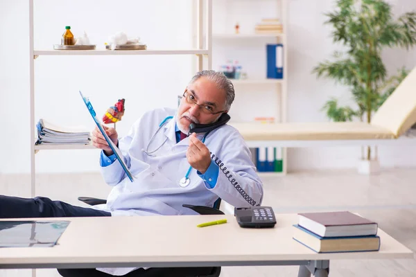 Velho médico falando por telefone na clínica — Fotografia de Stock