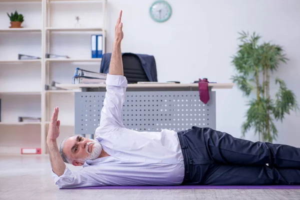 Ältere männliche Mitarbeiter machen in der Pause körperliche Übungen — Stockfoto