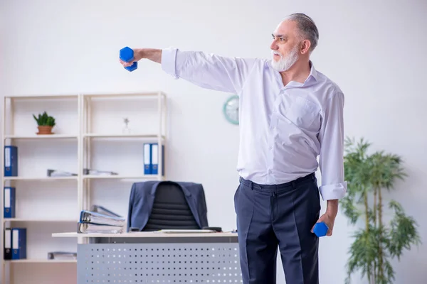 Verouderde mannelijke werknemer doet fysieke oefeningen tijdens de pauze — Stockfoto