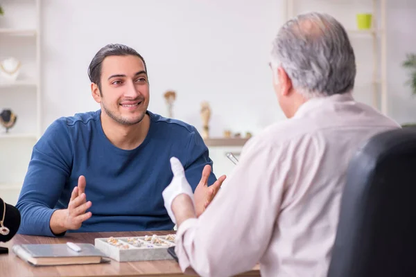 Joven visitando viejo joyero masculino — Foto de Stock