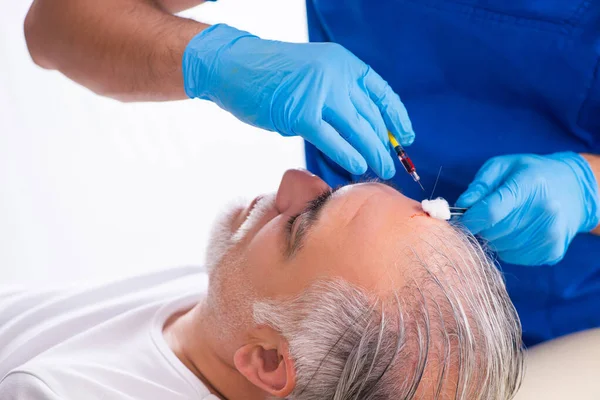 Gamle man besöker ung manlig läkare i hår transplantation conce — Stockfoto