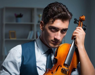 Genç müzisyen evde keman çalıyor.