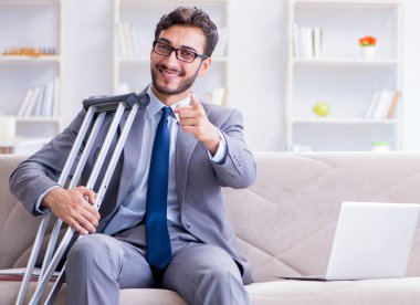 Koltuk değneği ve kırık bacağı olan bir iş adamı.