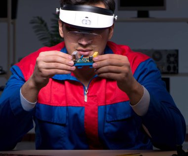 Bilgisayar uzmanı gece geç saatlerde bilgisayarı tamir ediyor.