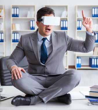Sanal gerçeklikteki iş adamı VR gözlükleri masanın üstünde meditasyon yapıyor.