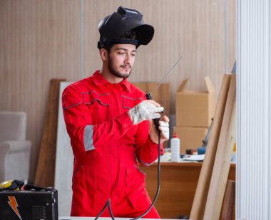 Kaynak tabancası elektrot ve kask takan genç bir tamirci.