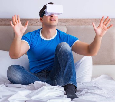 Yatakta sanal gerçeklik başlığı takan genç bir adam.