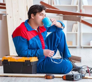 Genç marangoz ahşap kalaslarla çalışmaya ara veriyor.