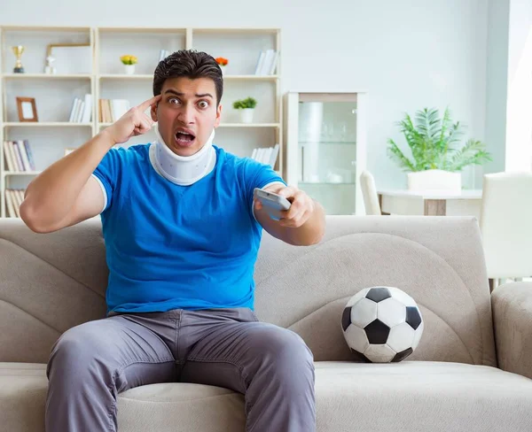 Egy férfi nyaksérüléssel focit néz otthon. — Stock Fotó