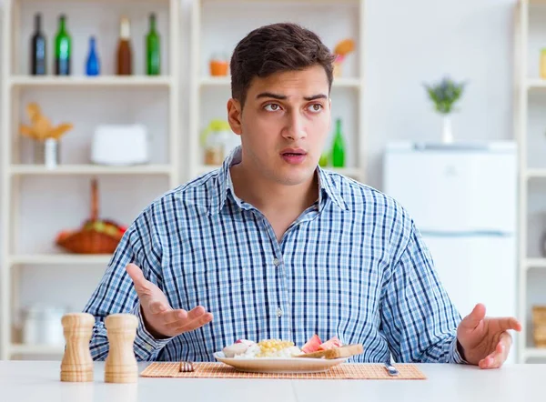 若い夫は昼食のために家で味のない食べ物を食べる — ストック写真
