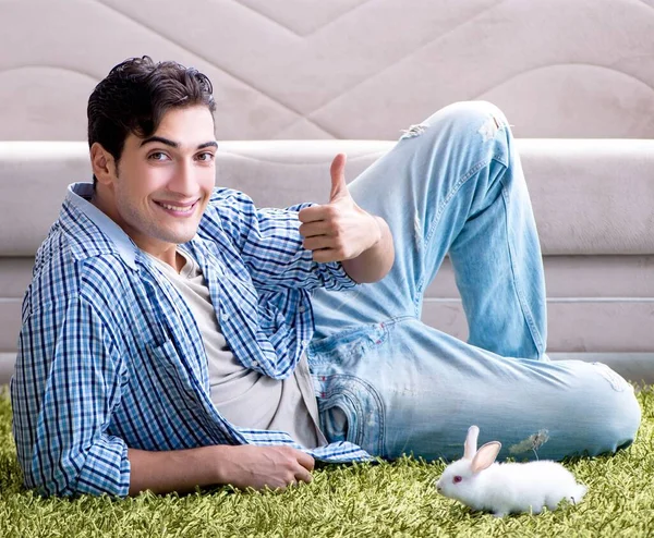 Junger Mann spielt zu Hause mit Kaninchen — Stockfoto