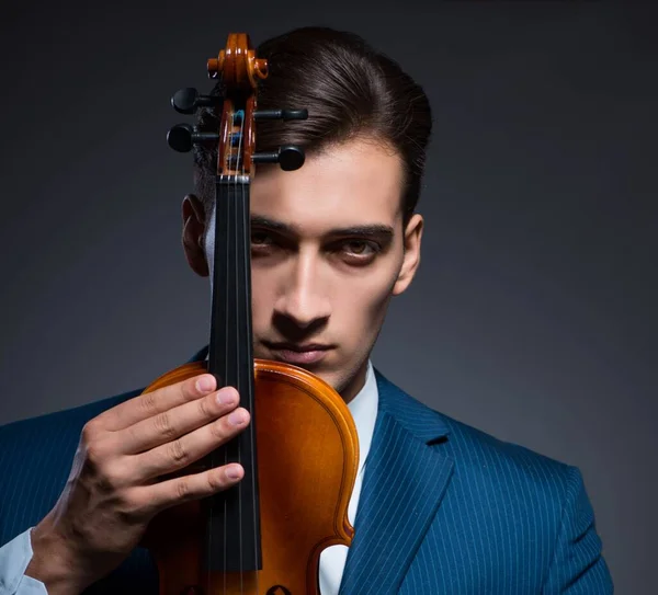Młody człowiek gra na skrzypcach w ciemnym pokoju — Zdjęcie stockowe
