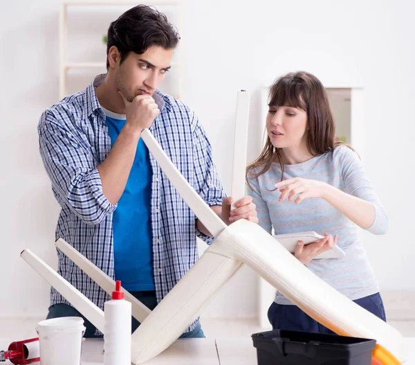 Ehefrau hilft Ehemann, kaputten Stuhl zu Hause zu reparieren — Stockfoto