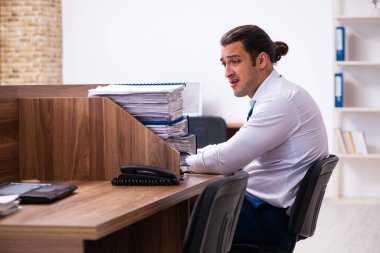 Ofisteki aşırı işten memnun olmayan genç bir erkek işçi.