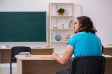 Yeşil panonun önünde genç bir erkek öğrenci.