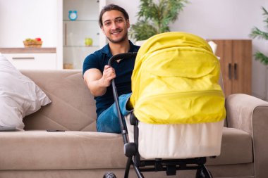 Genç baba yeni doğan bebeğe bakıyor.