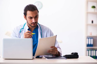 Klinikte çalışan genç erkek doktor.