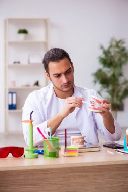 Klinikte çalışan genç erkek dişçi.