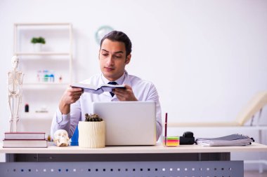 Klinikte kitap okuyan genç bir erkek doktor.