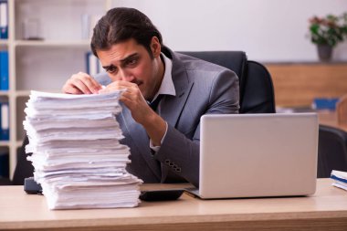 Ofisteki aşırı işten memnun olmayan genç bir erkek işçi.