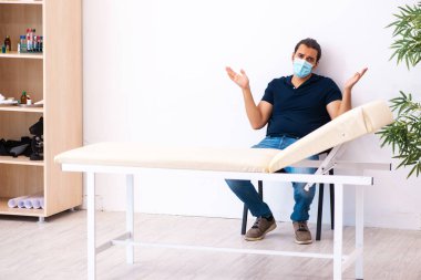 Genç adam hastanede salgın sırasında doktoru bekliyor.
