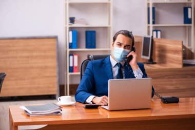 Ofiste maske takan genç bir erkek çalışan.