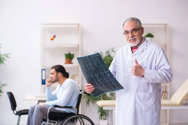坐在轮椅上的年轻人和老医生放射学家 — 图库照片