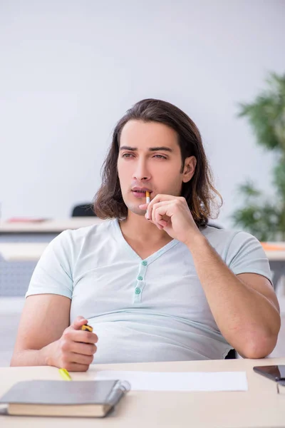 Fiatal férfi tanuló cigarettázik az osztályteremben — Stock Fotó