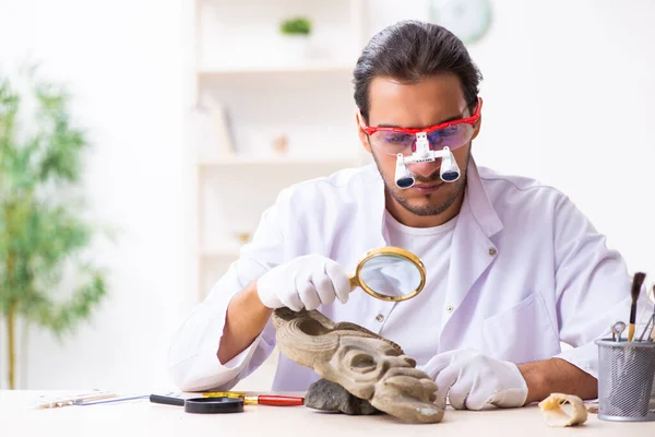 Jonge mannelijke archeoloog bestudeert het oude Afrikaanse steenmasker — Stockfoto