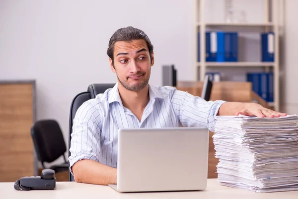 Joven empleado masculino y muchos papeles en la oficina — Foto de Stock