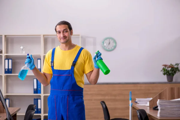 Jovem empreiteiro limpando o escritório — Fotografia de Stock