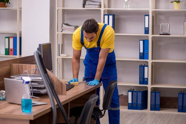 Jovem empreiteiro limpando o escritório — Fotografia de Stock