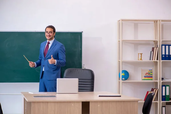 Junger männlicher Lehrer im Anzug vor grünem Brett — Stockfoto