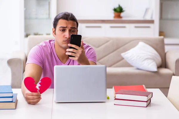 Young male student in one-sided love concept at home