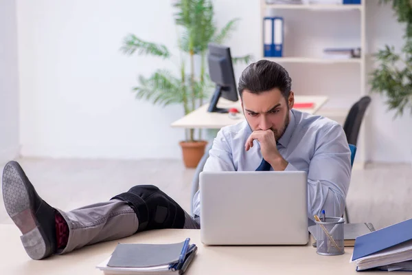 Young leg injured employee working in the office — Stock Photo, Image