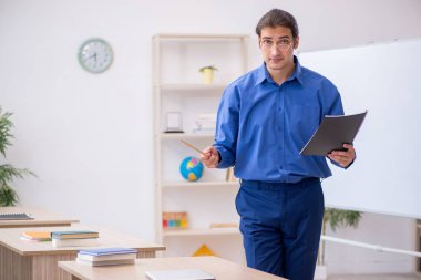 Beyaz tahtanın önünde genç bir erkek öğretmen.