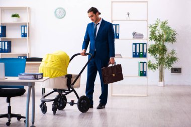 Genç erkek çalışan işyerinde çocuğa bakıyor.