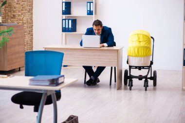 Genç erkek çalışan işyerinde çocuğa bakıyor.