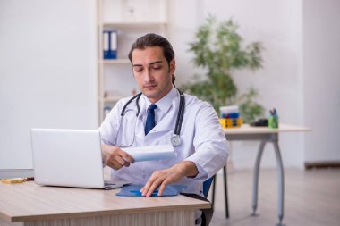 Genç erkek doktor hastanede not alıyor.