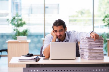 Ofisteki aşırı işten memnun olmayan genç bir erkek işçi.