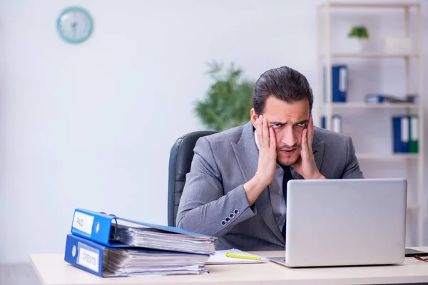 Jovem funcionário masculino infeliz com excesso de trabalho no escritório — Fotografia de Stock