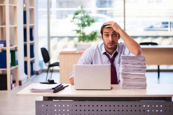 Jonge mannelijke werknemer ongelukkig met overmatig werk in het kantoor — Stockfoto