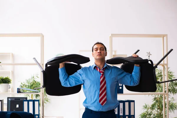 Joven empleado masculino haciendo ejercicios deportivos en el lugar de trabajo — Foto de Stock